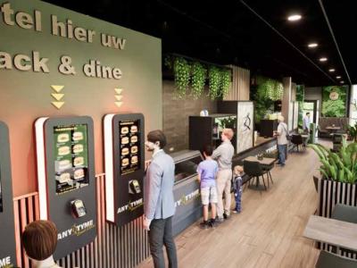 Moderne AnyTyme Snack & Dine met bestelzuilen en klanten in een groen ingerichte ruimte.