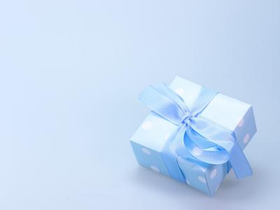 Lichtblauw cadeau met witte stippen en een strik op een effen achtergrond.