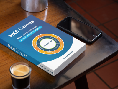 Boek met de titel MKB Canvas ligt op een tafel naast een espresso en smartphone.