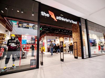 Voorgevel van The Athlete’s Foot winkel met etalagepop in sportkleding en klanten die binnen winkelen.
