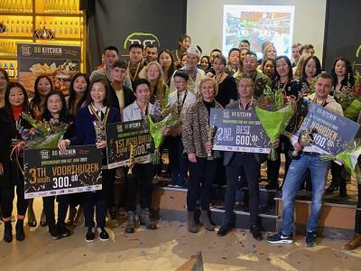 Groepsfoto van BB Kitchen medewerkers met prijzen en bloemen bij een ondernemersprijsuitreiking.