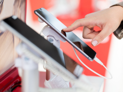 Hand bedient een iPhone in een winkel met meerdere smartphones op display.