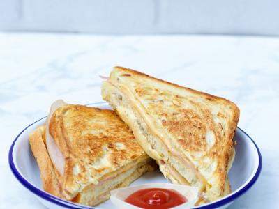 Op een bord liggen twee gegrilde tosti’s naast een schaaltje ketchup.