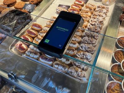 Betaalterminal van Buckaroo bij een bakkerijdisplay met diverse gebakjes en broden van 't Stoepje.