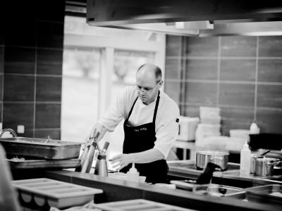 Chef-kok bereidt gerechten in een moderne, professionele keuken met diverse keukenapparatuur en ingrediënten.
