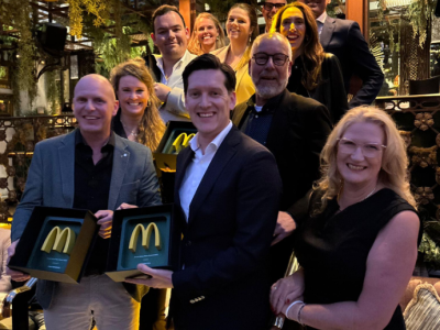 Een groep mensen poseert terwijl twee mannen een McDonald's award vasthouden in een sfeervol verlichte ruimte.