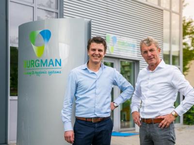 Twee mannen in zakelijke kleding poseren bij het kantoor van Burgman, leverancier van hygiënische systemen.