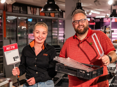 Medewerker in Coop-uniform en man met rode polo in supermarkt tonen actieprijsbord en plastic krat.