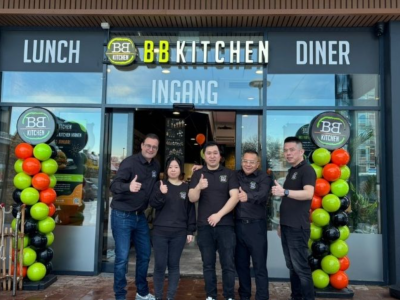 Teamleden poseren voor de ingang van BB Kitchen Vianen tijdens de feestelijke opening, omringd door ballonnen.