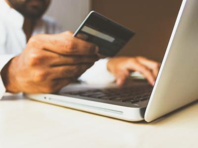 Persoon voert een transactie uit met een creditcard aan een laptop, benadrukt zakelijk gebruik in franchises.
