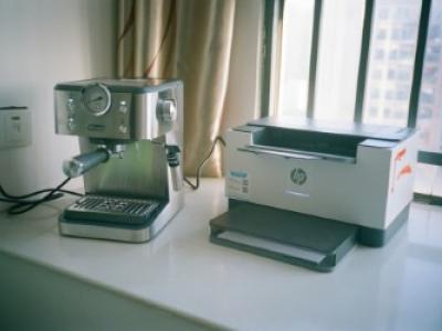 Espressomachine en printer naast elkaar op een tafel bij een raam.