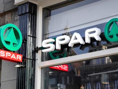 SPAR-winkelpui met logo's en reflectie van gebouwen in glas.