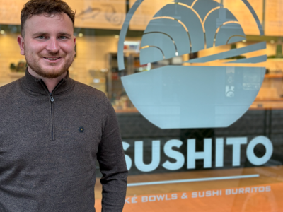 Man staat voor de ingang van een restaurant met de naam Sushito op het raam zichtbaar.
