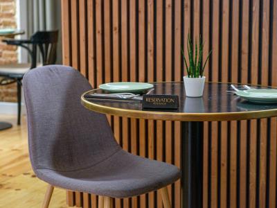 Een gereserveerde tafel in een modern restaurant met gedekte borden en een klein groen plantje.
