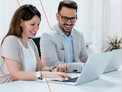 Twee mensen werken samen op laptops aan een tafel in een moderne, lichte kantooromgeving.