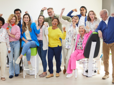Een diverse groep mensen viert enthousiast samen in een lichte fitnessruimte.