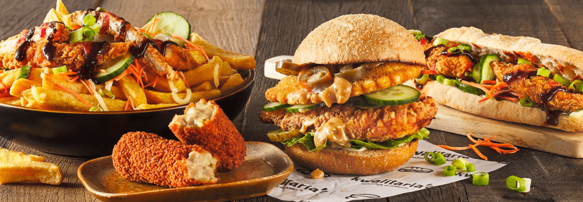 Verschillende Kwalitaria menu-opties, waaronder een broodje, wrap, friet met kip en een kroket op houten tafel.