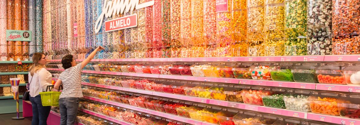 Binnenzicht van een Jamin-winkel in Almelo met kleurrijke snoepdispensers en klanten die snoep uitkiezen.