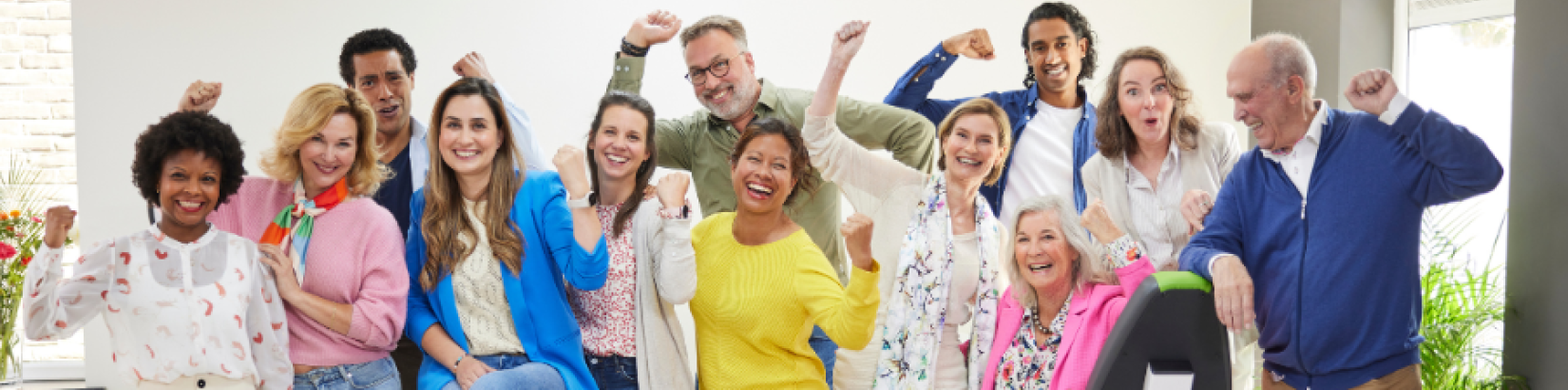 Een diverse groep mensen viert samen een succesvol moment in een lichte, moderne fitnessruimte.