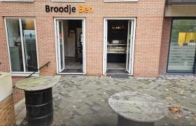 Gevel van Broodje Ben in Diemen met open deuren en zicht op de binnenkant, omringd door een betegeld terras met tafels.