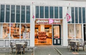 Gevel van Bakker Bart Zaltbommel met open deur en tafels buiten op de stoep.