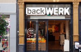 Vooraanzicht van de BackWERK winkel in Leiden centrum met open glazen deuren en fruitkisten bij de ingang.