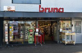 Buitenaanzicht van Bruna Bergeijk met duidelijke gevelsignage en rekken met boeken en kaarten bij de ingang.