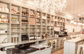 Interieur van een sfeervolle pizzeria met open keuken, houten meubels, voorraadrekken en een traditionele pizzaoven.